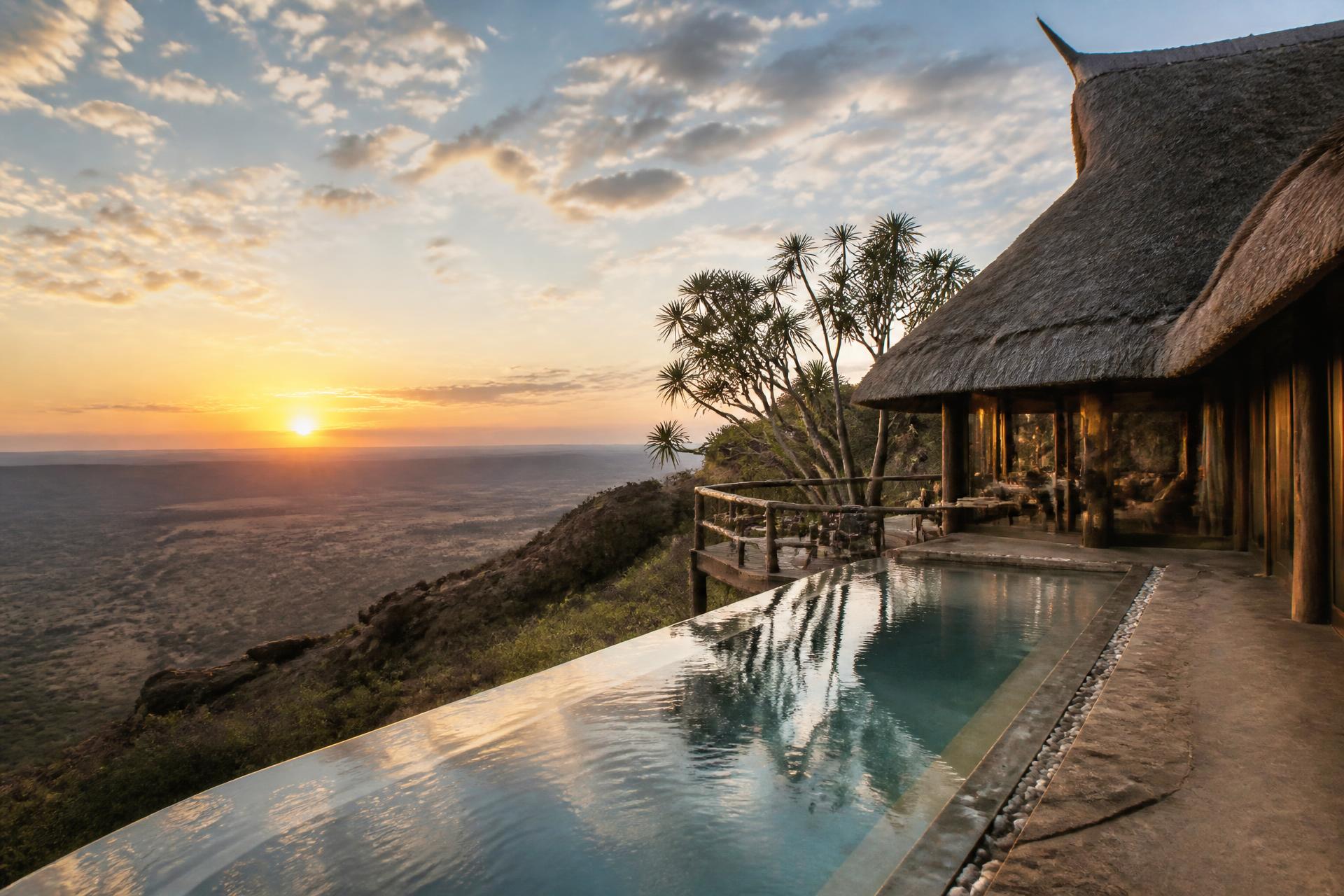 Arab traveller on the terrace of a private wilderness house at sunset, horses grazing below